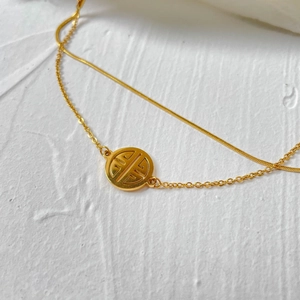 Detail of double-layered gold snake and link chain with hollow round pendant charm
