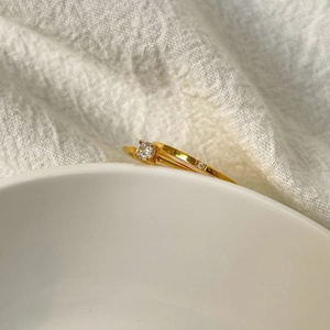 Detail of 18K gold plated titanium ring with round cubic zirconia and side stones