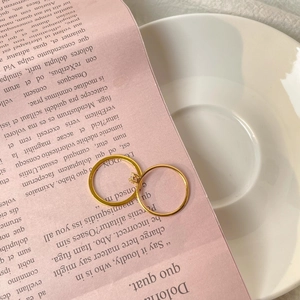 Close-up of elegant 18K gold plated rings set with a sparkling zircon on a ceramic dish