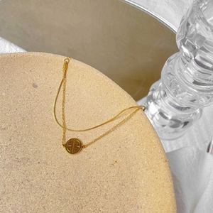 Detail view of a gold-plated double-layer bracelet with snake chain and hollow pendant