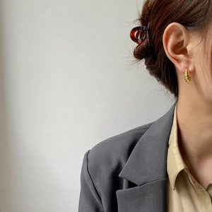 Detail of elegant gold croissant stud earrings and vintage amber hair clip worn on a model