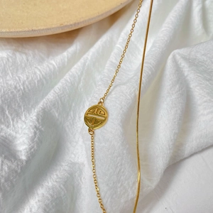 Close-up of a double-layered gold snake chain bracelet with a hollow round pendant