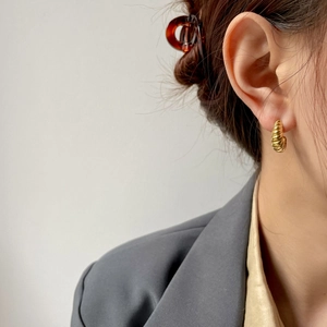 Detail of elegant gold croissant stud earring showing twisted texture on model ear