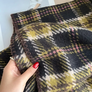 Gros plan sur l'écharpe épaisse à carreaux montrant la texture douce et les coutures