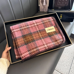 Gros plan d'une écharpe à carreaux rose avec étiquette de marque sur un plateau