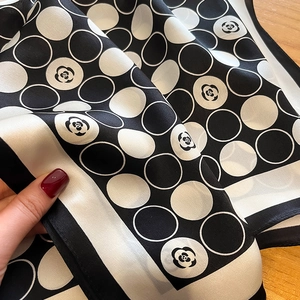 Silk scarf with classic polka dots and camellia pattern shown on a wooden background