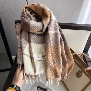 Detailed texture of thick plaid winter scarf with fringe and brand label on leather chair