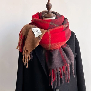 Detail of red and brown plaid scarf with fringe tassels on wool coat