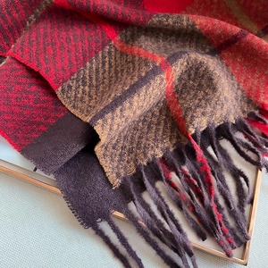 Detailed shot of soft plaid scarf featuring red tassels and classic British check pattern