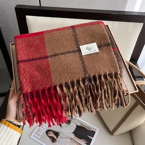 Close-up of thick reddish-brown checkered scarf with long tassels in a cozy setting