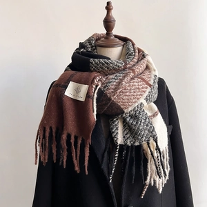 Close-up of brown and black plaid scarf with thick fringe and woven brand label