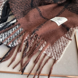 Detailed view of checkered scarf fringe and soft cashmere-like texture with brand tag