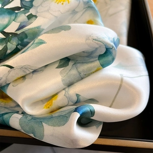 Élégant foulard en soie avec imprimés de camélias blancs drapé dans un coffret cadeau chic