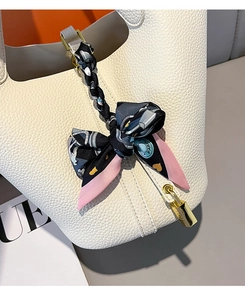 Detail of white lychee leather bucket bag with heart print silk scarf on handle
