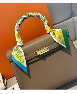 Detailed view of luxury brown leather handbag with silk scarf wrapped on handle