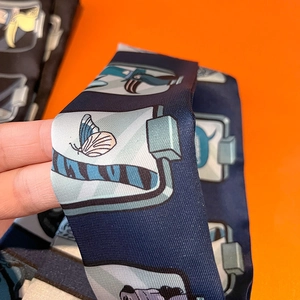 Detailed view of dark blue twill silk scarf with cartoon butterfly prints and smooth texture