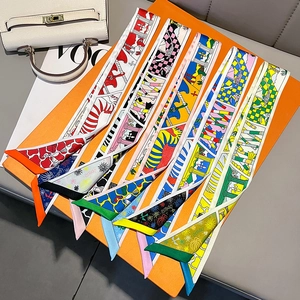 Elegant silk twilly scarves with vibrant prints on luxury handbag and orange gift box