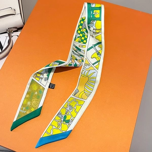 Macro detail of geometric print silk twilly scarf on orange gift box with handbag