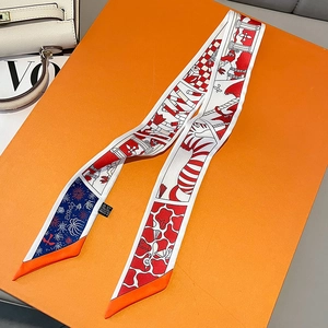 Detail of red and white patterned narrow twilly silk scarf draped on an orange gift box