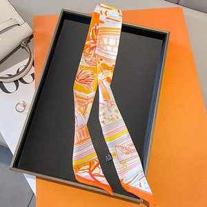 Detail of a luxury orange silk twilly scarf with nautical print on a display tray