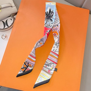 Detailed close-up of a satin twilly scarf with abstract prints on an orange gift box