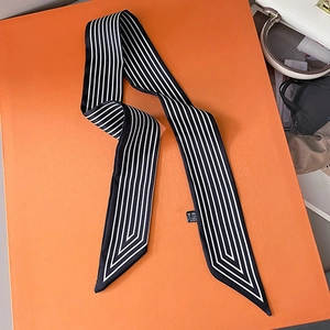 Gros plan détaillé d'un foulard twilly à rayures noires et blanches sur un fond orange vif