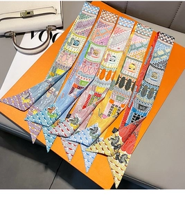 Macro detail of five luxury silk twilly scarves with equestrian prints on orange gift box