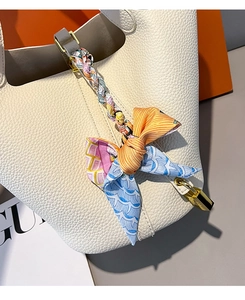 Close-up of white lychee grain leather bucket bag with printed silk scarf handle