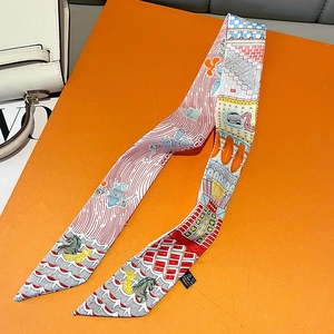 Detail of printed twilly silk scarf tied on a white handbag with orange gift box