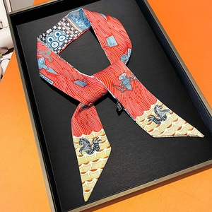 Close-up of silk twilly ribbon featuring red seahorse patterns on orange gift box