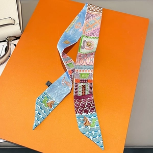 Close-up of a printed satin twilly silk scarf tied on a bag handle with ocean patterns