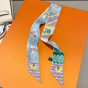 Detailed view of printed silk twilly scarf for handbag handles on luxury orange gift box