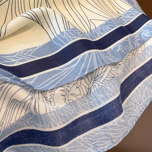 Elegant vintage scarf featuring blue leaf patterns and geometric stripes on cream twill fabric