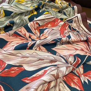 Close-up of tropical leaf print silk scarf with twill texture and CHANGE branding