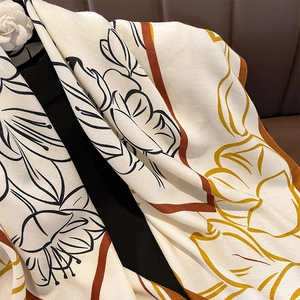 Détail d'une écharpe tissée à chevrons avec imprimé floral et accents dorés