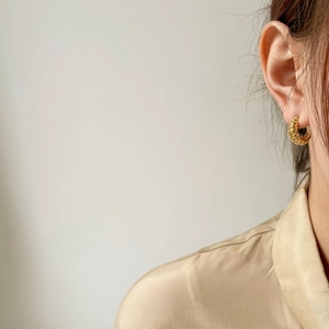 Elegant gold twisted croissant dome earrings worn by a model in a minimalist French style