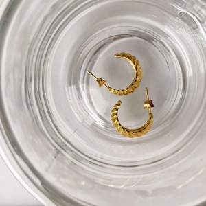 Macro detail of French style gold croissant stud earrings with elegant spiral twist texture