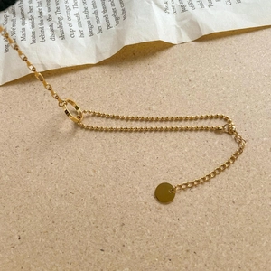 Detail of golden double-layer bracelet with bead chain and rectangular links