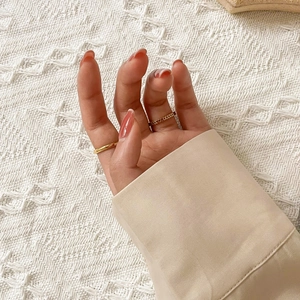 Close-up of minimalist gold ring and openwork heart design on a soft knit background