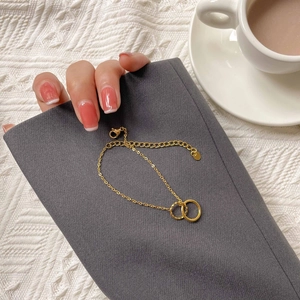 Detail of gold interlocking double circle bracelet held by a hand on a cozy background