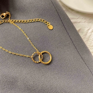 Close-up of golden interlocking rings pendant with textured finish on a chic grey fabric