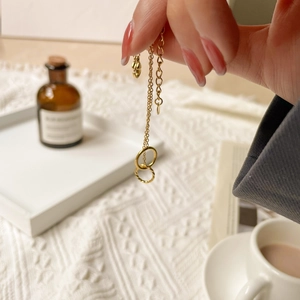 Detail of elegant gold double interlocking circle necklace over soft white knit textures