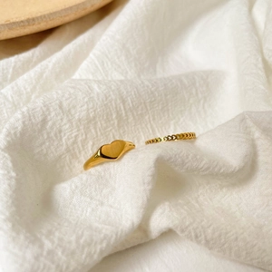 Minimalist gold heart ring set featuring a smooth signet ring and hollow heart band