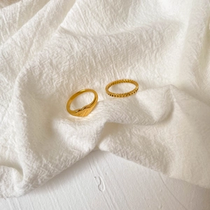 Detail of two gold heart rings: a solid signet heart and a hollow cutout heart band
