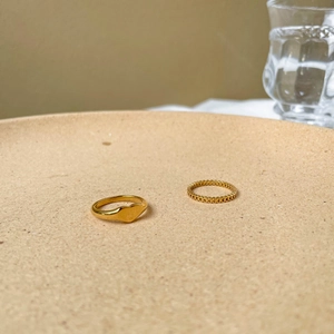 Close-up of gold-plated hollow heart rings on a ceramic tray with warm lighting