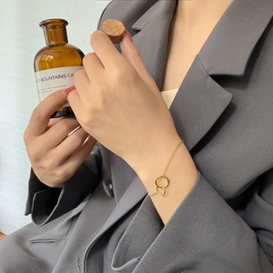Close-up of golden double-circle intertwined charm bracelet on woman wrist