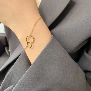 Close-up of golden double interlocking circles bracelet on wrist with elegant suit background