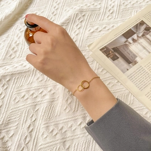 Detailed close-up of a double-ring gold bracelet with twisted and smooth texture details