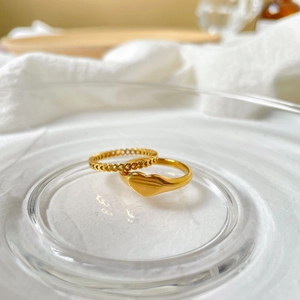 Close-up of minimalist heart cutout and heart-embossed gold metal rings on fabric