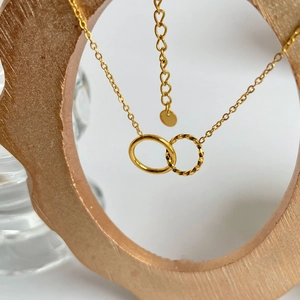 Detail of gold double interlocking rings necklace with twisted texture and smooth finish